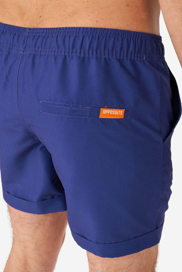 Man met blauwe zomerset bestaande uit shirt en korte broek, close-up van de korte broek vanaf de achterkant