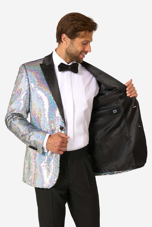 Man in sequin smoking met holografische zilveren pailletten en zwarte satijnen revers, gecombineerd met een wit overhemd, zwarte vlinderdas en zwarte broek.