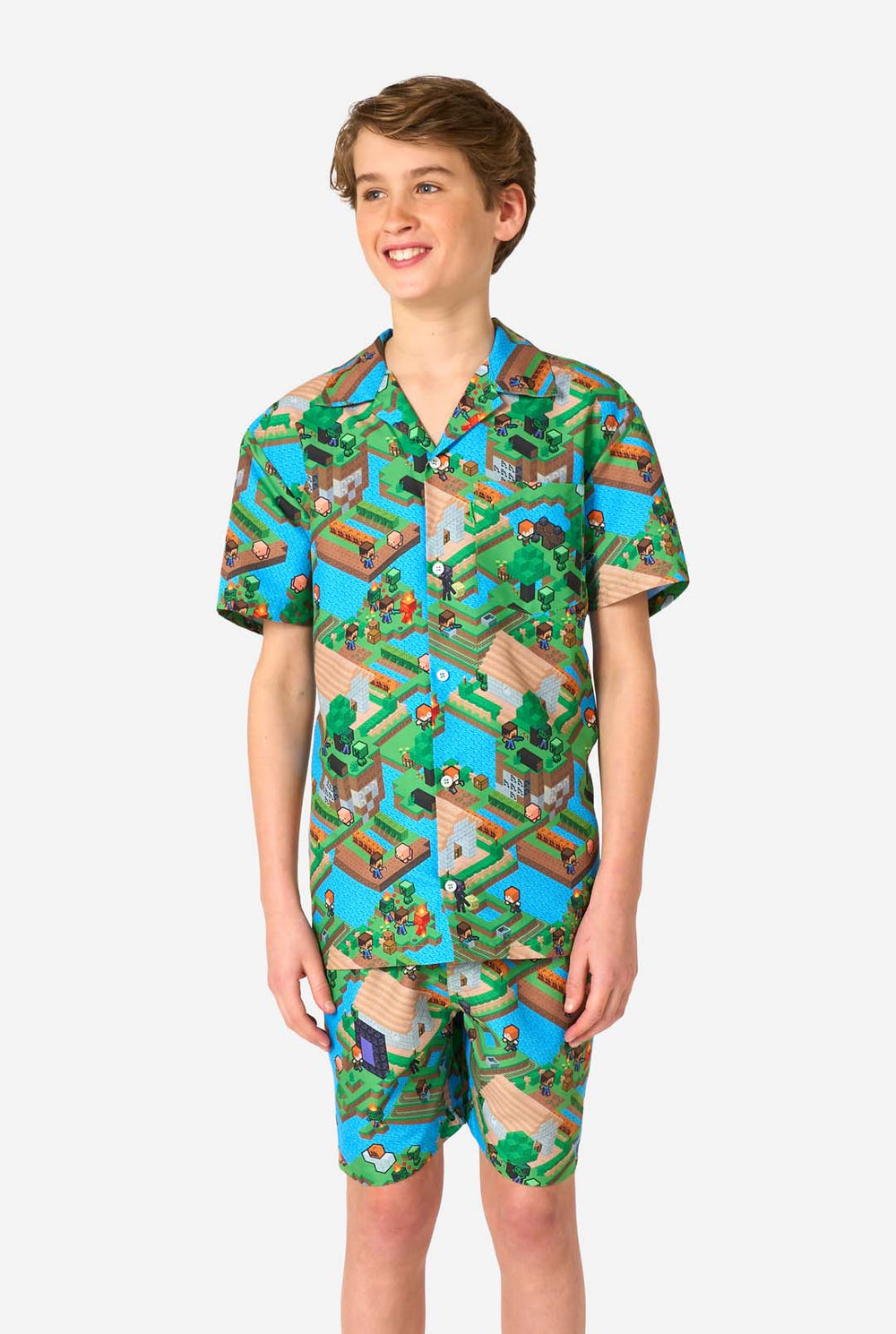 Een tiener draagt een kleurrijke zomeroutfit met een Minecraft Overworld print, met pixelachtige landschappen, personages en elementen uit het iconische spel. Het shirt met korte mouwen en de bijpassende shorts benadrukken een levendig ontwerp geïnspireerd door het Minecraft-universum.