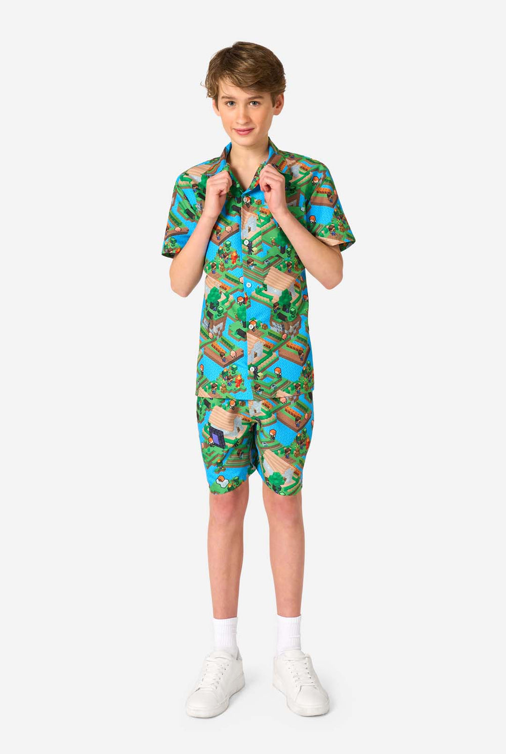 Een tiener draagt een kleurrijke zomeroutfit met een Minecraft Overworld print, met pixelachtige landschappen, personages en elementen uit het iconische spel. Het shirt met korte mouwen en de bijpassende shorts benadrukken een levendig ontwerp geïnspireerd door het Minecraft-universum.