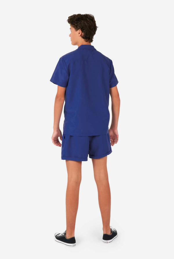 Jongen draagt ​​donkerblauwe zomerset, bestaande uit korte broek en shirt, gezien vanaf de achterkant