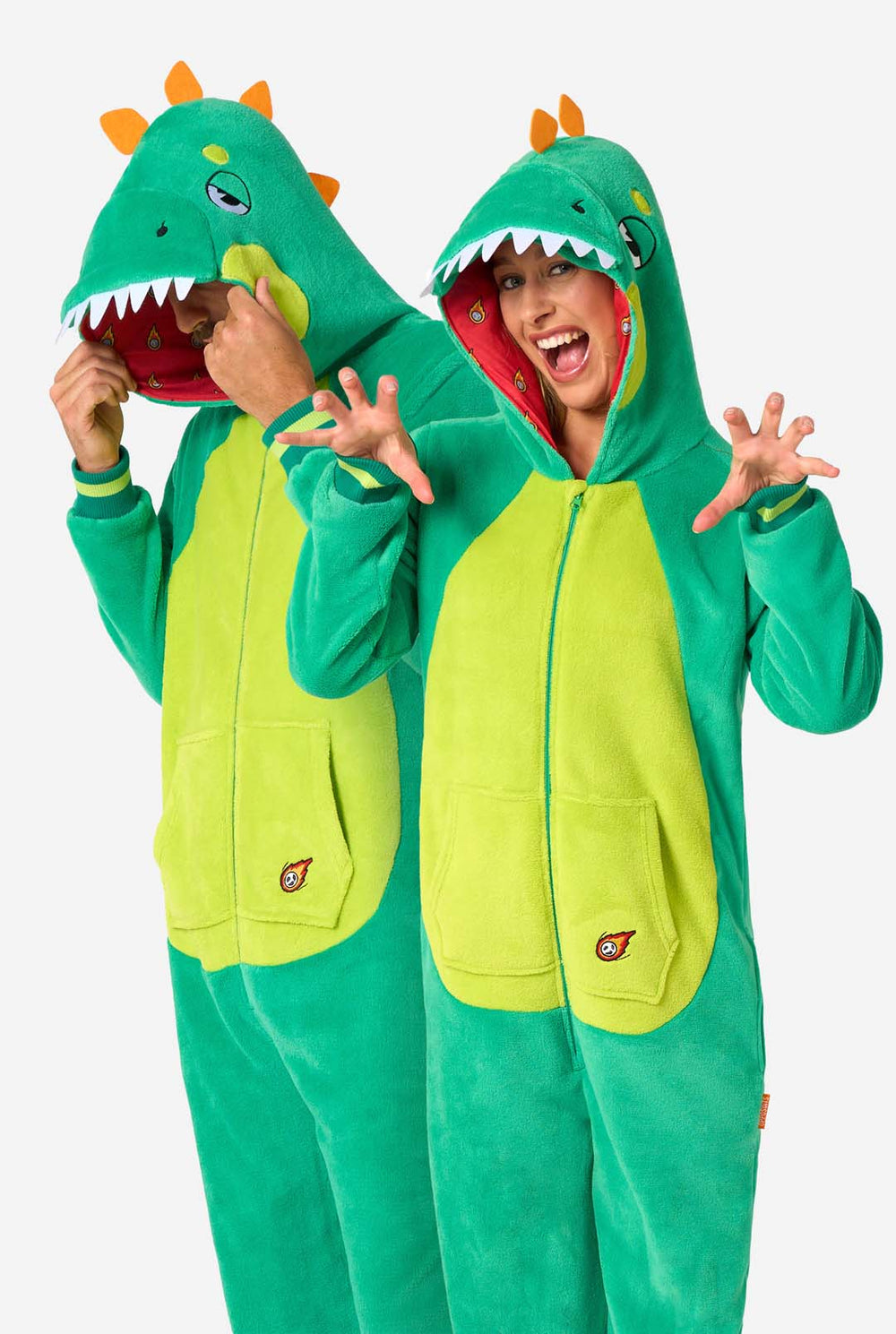 Een man en een vrouw dragen een groene dinosaurus onesie voor volwassenen met speelse capuchondetails en zacht, comfortabel materiaal. Ideaal om in te loungen of voor een verkleedpartijtje.