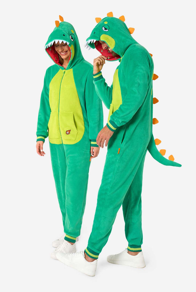 Een man en een vrouw dragen een groene dinosaurus onesie voor volwassenen met speelse capuchondetails en zacht, comfortabel materiaal. Ideaal om in te loungen of voor een verkleedpartijtje.