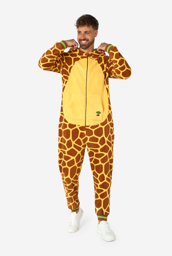 Een glimlachende man draagt ​​een bruin-gele volwassen onesie ontworpen als een giraffe. De onesie heeft een capuchon die lijkt op een giraffenkop en giraffedetails, perfect voor gezellig loungen of verkleedfeestjes. Volledig lichaamsbeeld met de kap naar beneden.