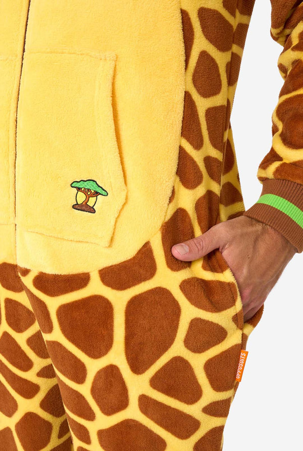 Een glimlachende man draagt ​​een bruin-gele volwassen onesie ontworpen als een giraffe. De onesie heeft een capuchon die lijkt op een giraffenkop en giraffedetails, perfect voor gezellig loungen of verkleedfeestjes. Zak close-up.