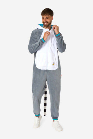 Een man draagt ​​een grijze en witte maki onesie voor volwassenen met speelse capuchondetails en gezellig, zacht materiaal, perfect voor loungen of verkleedevenementen. Inclusief zwart-witte staart. Volledig lichaamsbeeld met de kap op zijn rug en zichtbare staart.