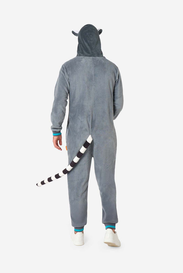 Een man draagt ​​een grijze en witte maki onesie voor volwassenen met speelse capuchondetails en gezellig, zacht materiaal, perfect voor loungen of verkleedevenementen. Inclusief zwart-witte staart. Afbeelding van het volledige lichaam met de achterkant van de onesie.