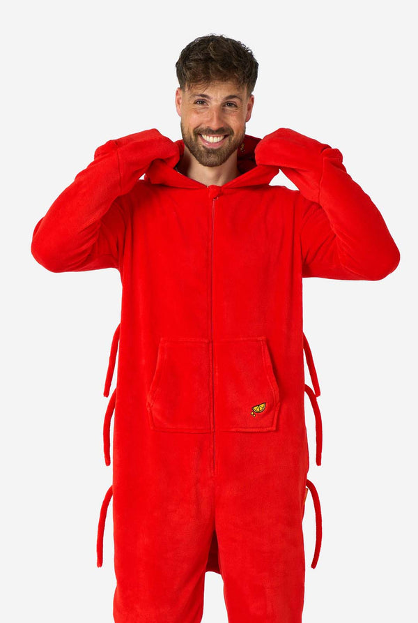 Een man draagt ​​een felrode onesie voor volwassenen met een kreeftenthema, speelse capuchondetails en gezellig, zacht materiaal, perfect voor loungen of verkleedevenementen. inclusief gestikte handschoenen als klauwen. Hood ligt op zijn rug.