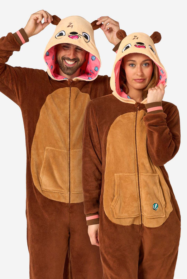 Een lachende man en een vrouw dragen een bruine onesie voor volwassenen met de afbeelding van een otter. De onesie heeft een capuchon met oren, een schattig gezichtje en speelse otterdetails, perfect voor een gezellig loungen of verkleedpartijtje.