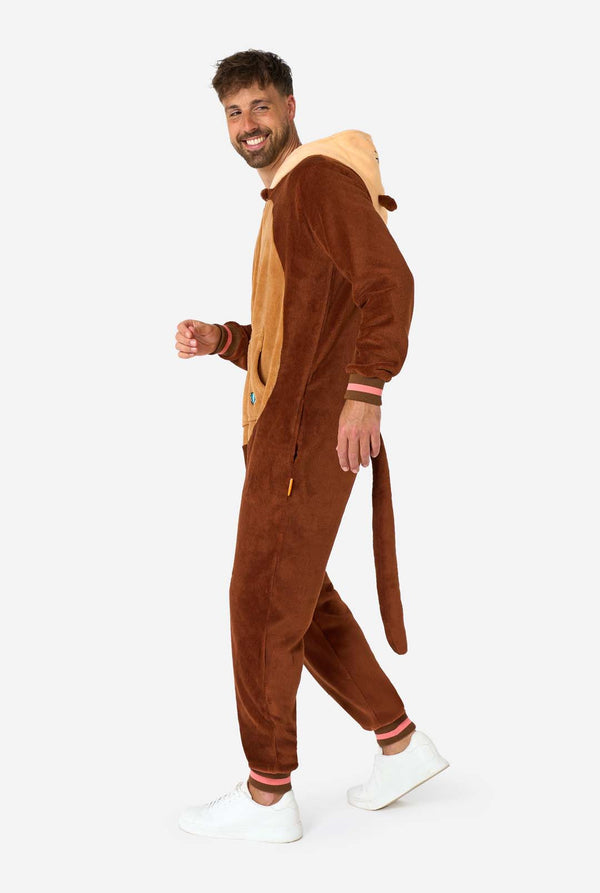 Een glimlachende man draagt ​​een bruine volwassen onesie ontworpen als een otter. De onesie heeft een capuchon met oren, een schattig gezichtje en speelse otterdetails, perfect voor gezellig loungen of verkleedfeestjes. Afbeelding van het volledige lichaam met de zijkant van de onesie.