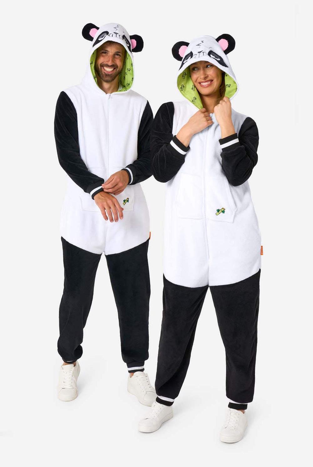Een man en een vrouw dragen een onesie voor volwassenen met een pandathema. Deze comfortabele onesie is uitgevoerd in zwart-witte pandakleuren en heeft een speelse capuchon met panda-oren en een schattig gezichtje. Perfect om in te loungen of voor een leuk verkleedfeestje.