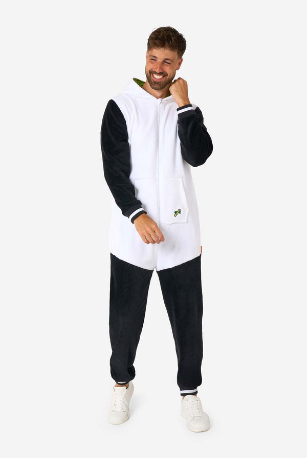 Een glimlachende man die een volwassen onesie met panda-thema draagt. Deze gezellige onesie heeft de zwart-witte pandakleuren met een speelse capuchon met panda-oren en een schattig gezichtje. Perfect voor loungen of leuke verkleedgelegenheden. Volledig lichaamsbeeld met de capuchon op zijn rug.