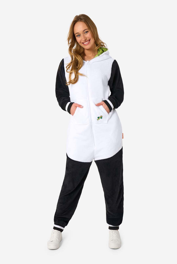 Een vrouw draagt ​​een onesie voor volwassenen met een pandathema. Deze comfortabele onesie is uitgevoerd in zwart-witte pandakleuren en heeft een speelse capuchon met panda-oren en een schattig gezichtje. Perfect om in te loungen of voor een leuk verkleedfeestje.