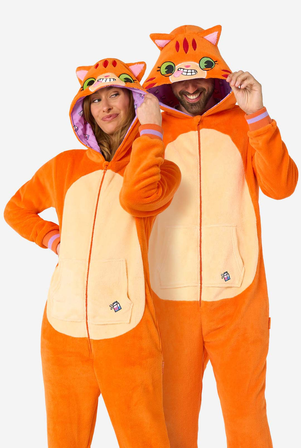 Een man en een vrouw dragen een oranje onesie voor volwassenen die is ontworpen als een rode katten onesie. De onesie heeft een capuchon die lijkt op het hoofd van een kat en katten details, perfect voor gezellig loungen of verkleed feestjes. Beiden hebben de capuchon op hun hoofd.