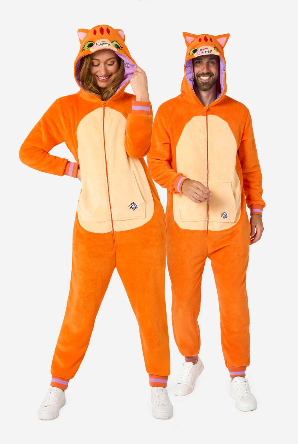 Een man en een vrouw dragen een oranje onesie voor volwassenen die is ontworpen als een rode katten onesie. De onesie heeft een capuchon die lijkt op het hoofd van een kat en katten details, perfect voor gezellig loungen of verkleed feestjes. Beiden hebben de capuchon op hun hoofd.