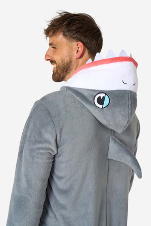 Een man draagt ​​een grijze en witte haaienonesie voor volwassenen met speelse capuchondetails en gezellig, zacht materiaal, perfect voor loungen of verkleedevenementen. Bovenlichaam close-up vanaf de achterkant.
