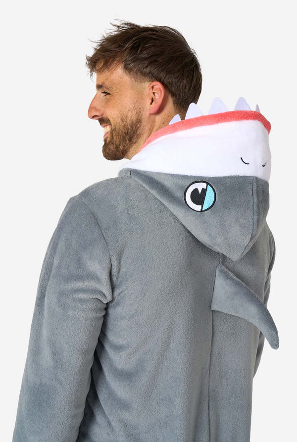 Een man draagt ​​een grijze en witte haaienonesie voor volwassenen met speelse capuchondetails en gezellig, zacht materiaal, perfect voor loungen of verkleedevenementen. Bovenlichaam close-up vanaf de achterkant.