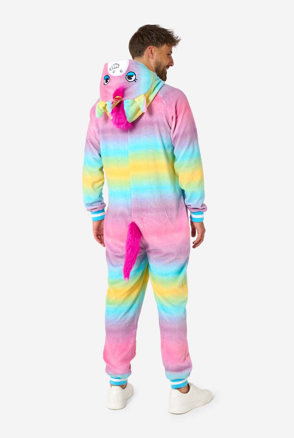 Een man draagt ​​een kleurrijke volwassen onesie ontworpen als een regenboogeenhoorn. De onesie heeft een levendig verloop van pastelkleuren, een gouden hoorn en speelse eenhoorndetails, perfect voor gezellig loungen of verkleedfeestjes. De capuchon ligt plat op zijn rug. Uitzicht vanaf de achterkant.