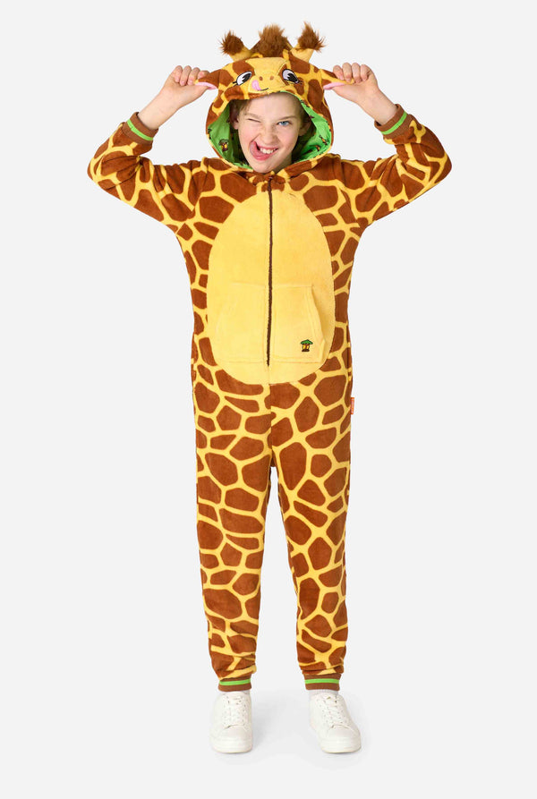 Een lachend kind draagt ​​een bruin-gele kinderonesie ontworpen als een giraffe. De onesie heeft een capuchon die lijkt op een giraffenkop. Volledig lichaamsbeeld.