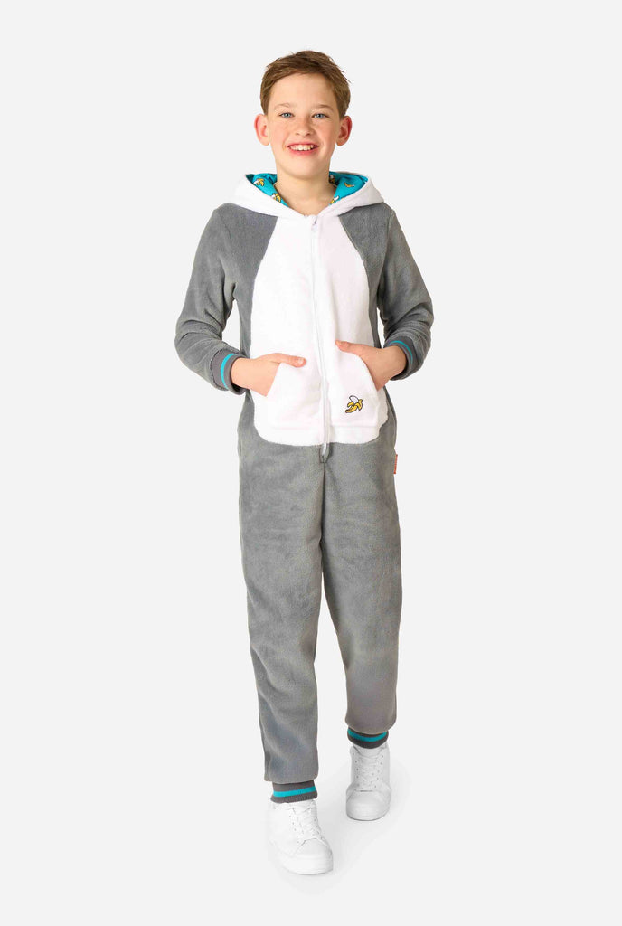 Een kind draagt ​​een comfortabel unisex kinderonesie in de vorm van een maki. De stof is gemaakt van grijs en wit pluche, heeft een capuchon met een cartoonmakigezicht en -oren en een speelse bananenprint op de zak. Volledig lichaam.