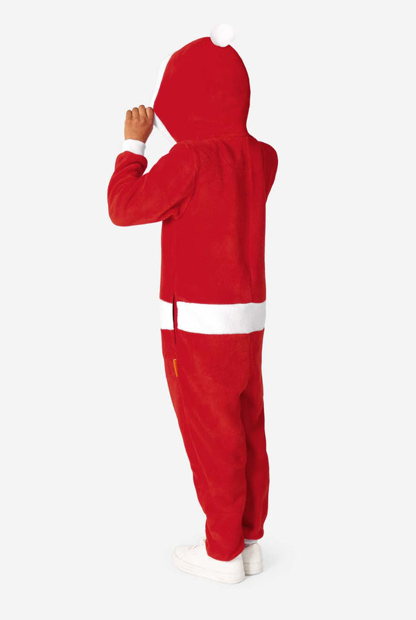 Kind dat iets zijwaarts gedraaid staat en de capuchon van een rode Santa-onesie optilt, waardoor de witte pompon op de achterkant zichtbaar is.