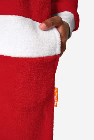 Close-up van de hand van een kind in de zak van een rode Santa-onesie, met zicht op de witte taille-afwerking en een oranje OppoSuits-label.