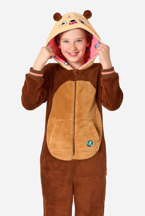 Een lachend kind draagt ​​een bruine kinderonesie ontworpen als een otter. De onesie heeft een capuchon met oren, een schattig gezichtje en speelse otterdetails.