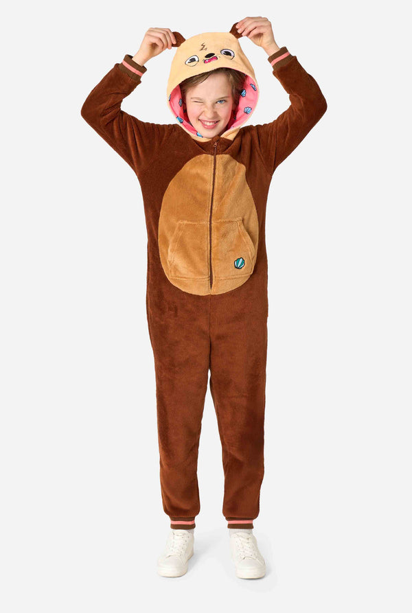 Een lachend kind draagt ​​een bruine kinderonesie ontworpen als een otter. De onesie heeft een capuchon met oren, een schattig gezichtje en speelse otterdetails. Volledig lichaamsbeeld.