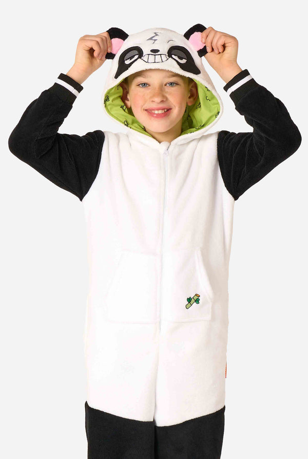 Een glimlachend kind dat een kinderonesie met panda-thema draagt. Deze gezellige onesie heeft de zwart-witte pandakleuren met een speelse capuchon met panda-oren en een schattig gezichtje. Perfect voor loungen of leuke verkleedgelegenheden.