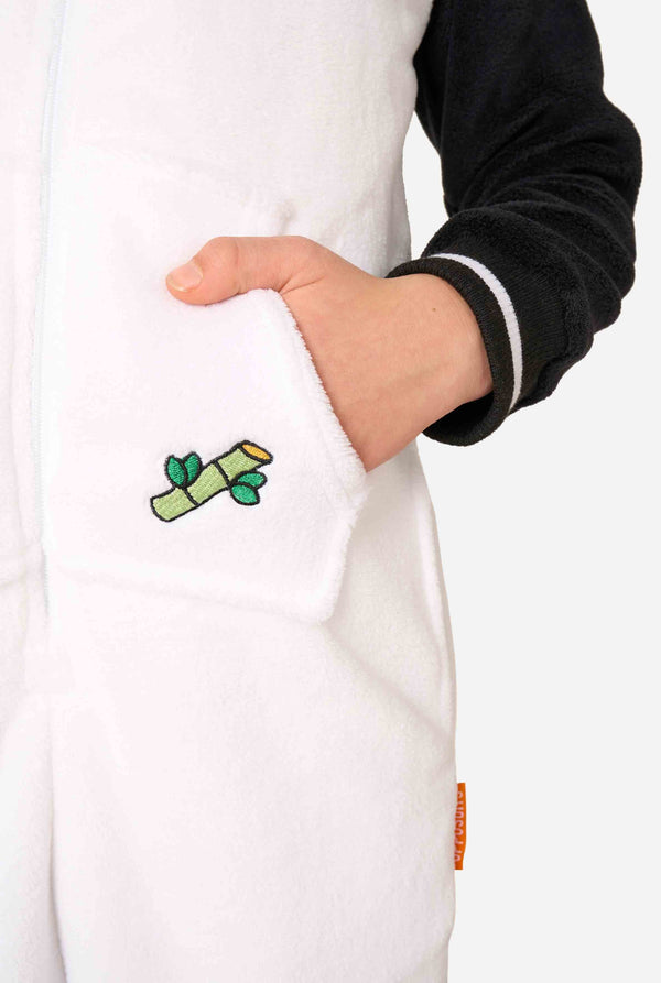 Een glimlachend kind dat een kinderonesie met panda-thema draagt. Deze gezellige onesie heeft de zwart-witte pandakleuren met een speelse capuchon met panda-oren en een schattig gezichtje. Perfect voor loungen of leuke verkleedgelegenheden. Close-up.