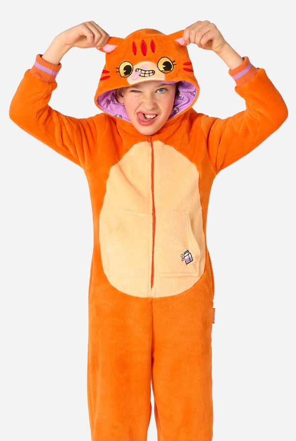 Kind draagt ​​een speels unisex kinderonesie in de vorm van een rood-oranje kat, met een capuchon met een cartoonkattengezicht, oren en een lichtbeige buikpaneel, dat een gek gezicht vormt tegen een effen achtergrond.