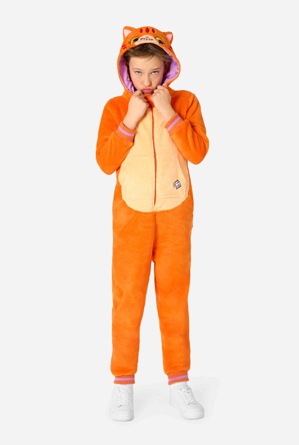 Kind draagt ​​een speels unisex kinderonesie in de vorm van een rood-oranje kat, met een capuchon met een cartoonkattengezicht, oren en een lichtbeige buikpaneel, dat een gek gezicht vormt tegen een effen achtergrond.