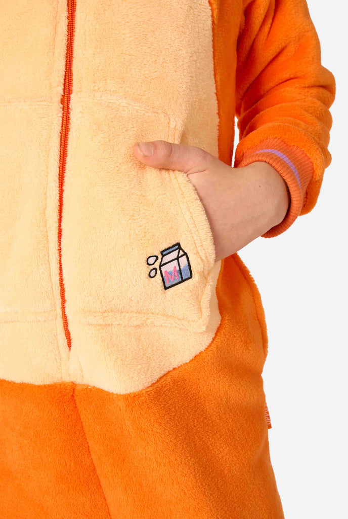 Kind draagt ​​een speelse unisex onesie voor kinderen, ontworpen als een rood-oranje kat, met een capuchon met een cartoonkattengezicht, oren en een lichtbeige buikpaneel, tegen een effen achtergrond. De focus ligt op een hand in een zak.