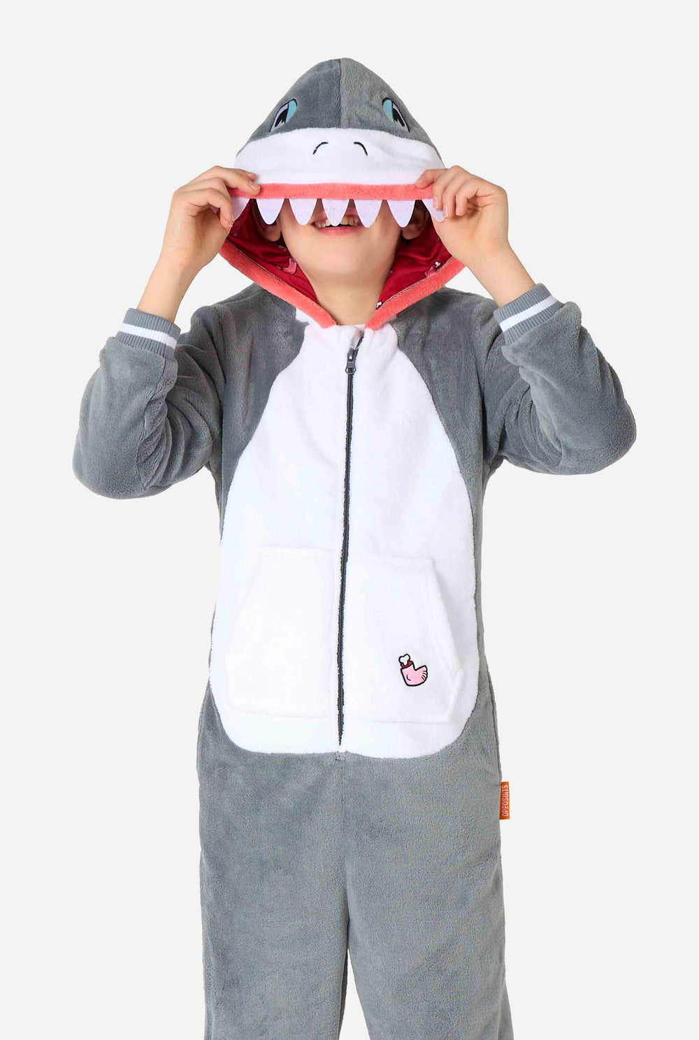 Een kind draagt ​​een grijze en witte kinderonesie met een haai, speelse capuchondetails en gezellig, zacht materiaal, perfect voor loungen of verkleedevenementen.