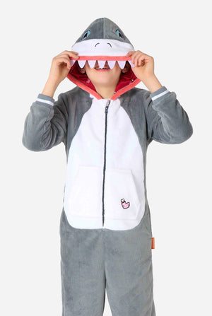 Een kind draagt ​​een grijze en witte kinderonesie met een haai, speelse capuchondetails en gezellig, zacht materiaal, perfect voor loungen of verkleedevenementen.