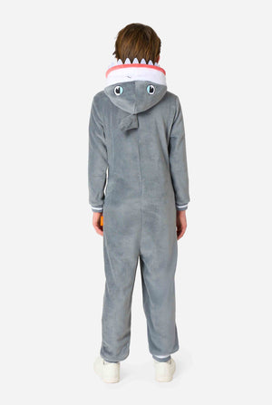 Een kind draagt ​​een grijze en witte kinderonesie met een haai, speelse capuchondetails en gezellig, zacht materiaal, perfect voor loungen of verkleedevenementen. Uitzicht vanaf de achterkant.