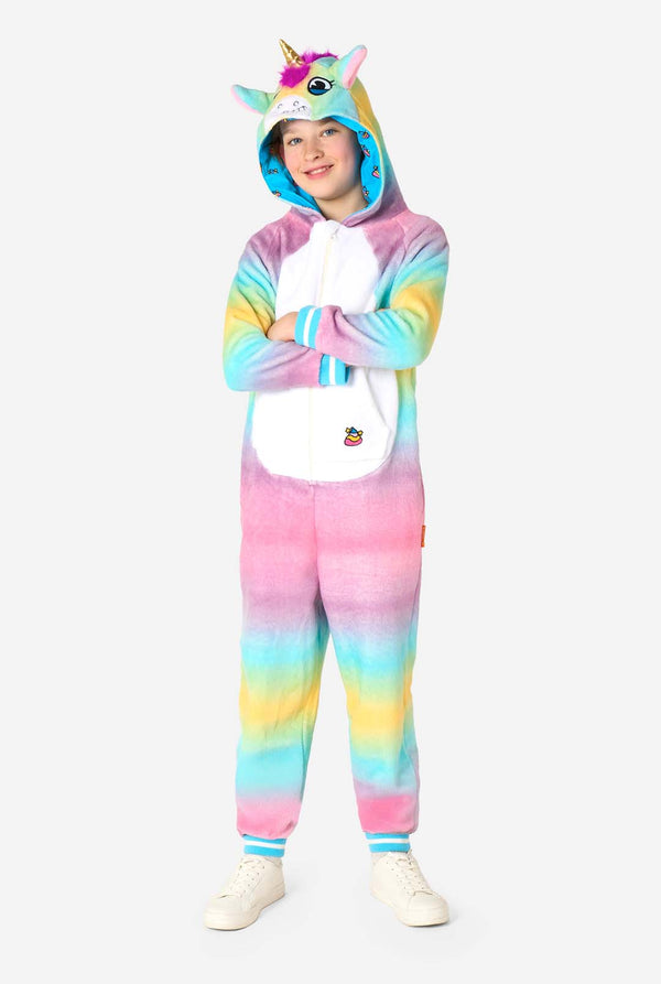 Een lachend kind draagt ​​een witte, roze, blauwe en gele kinderonesie ontworpen als eenhoorn. De Unicorn onesie heeft een capuchon die lijkt op een eenhoornkop en andere speelse details. Volledig lichaamsbeeld.