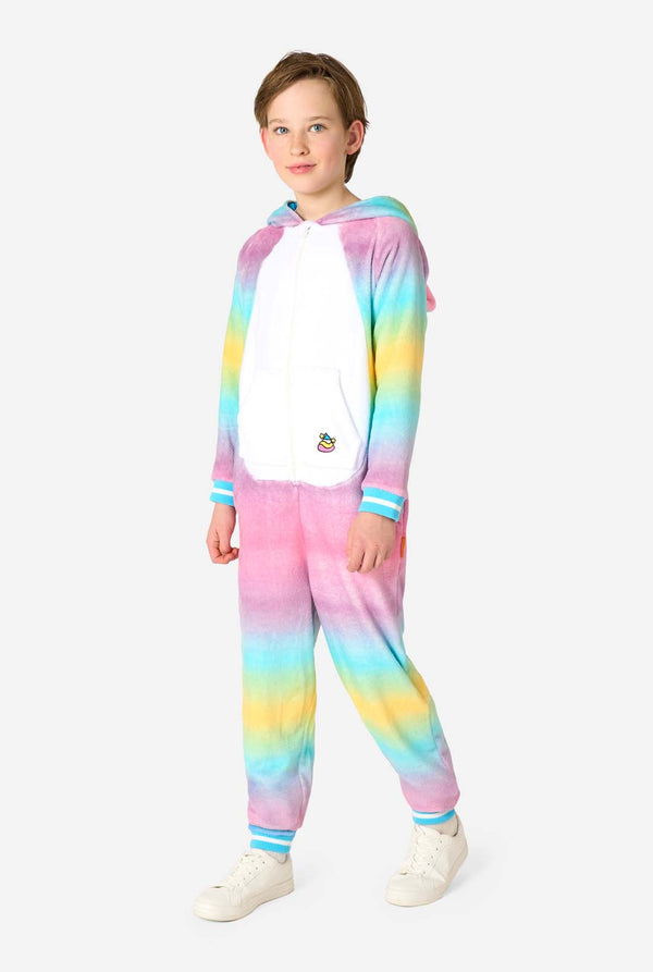 Een lachend kind draagt ​​een witte, roze, blauwe en gele kinderonesie ontworpen als eenhoorn. De Unicorn onesie heeft een capuchon die lijkt op een eenhoornkop en andere speelse details. Volledig lichaamsbeeld met de kap naar beneden.