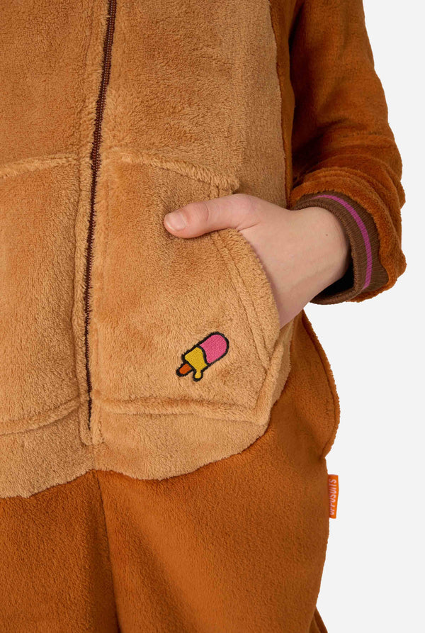 Een vrolijk jongetje in een bruine kinderonesie ontworpen als walrus. De onesie heeft een capuchon met hoektanden, gestikte handschoenen die op poten lijken en speelse walrusdetails, perfect voor gezellig loungen of verkleedfeestjes. Close-up.