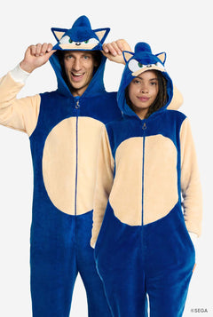 Een man en een vrouw dragen een speelse blauw-beige onesie voor volwassenen met Sonic the Hedgehog-thema van OppoSuits. De comfortabele onesie heeft een ritssluiting aan de voorkant en een capuchon die is ontworpen om te lijken op Sonics iconische gezicht, compleet met oren en een expressieve blik. De blauwe romp van het pak contrasteert met een beige buik, wat Sonics klassieke look nabootst.