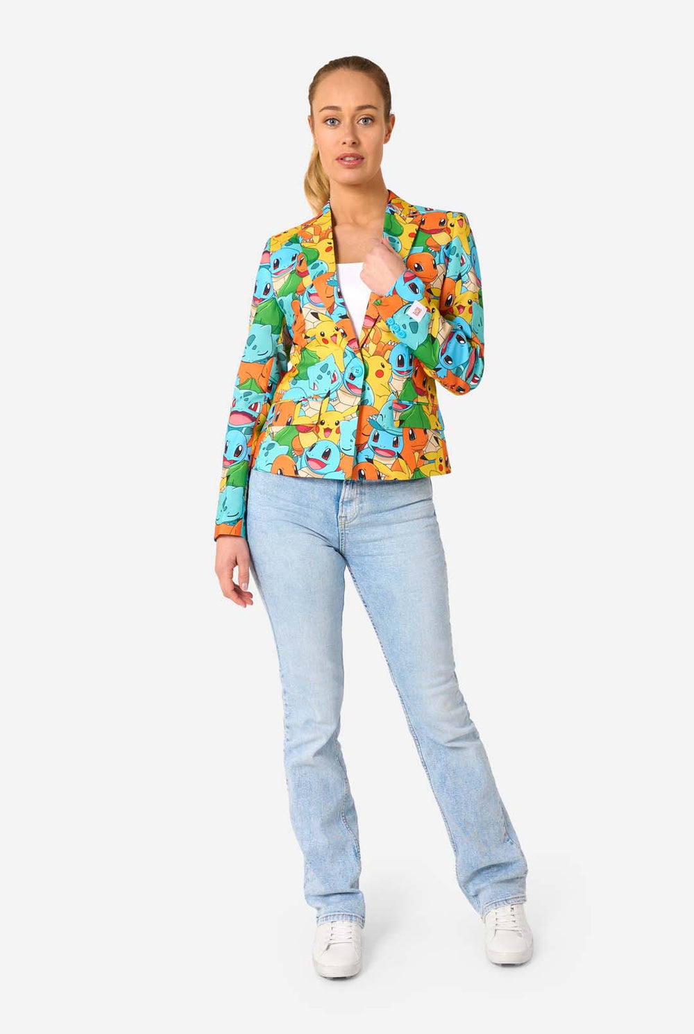 Vrouw draagt een veelkleurige pokemonblazer met personages als pikachu, squirtle, charmander en bulbasaur. Ze houdt het jasje vast en lacht in de camera.