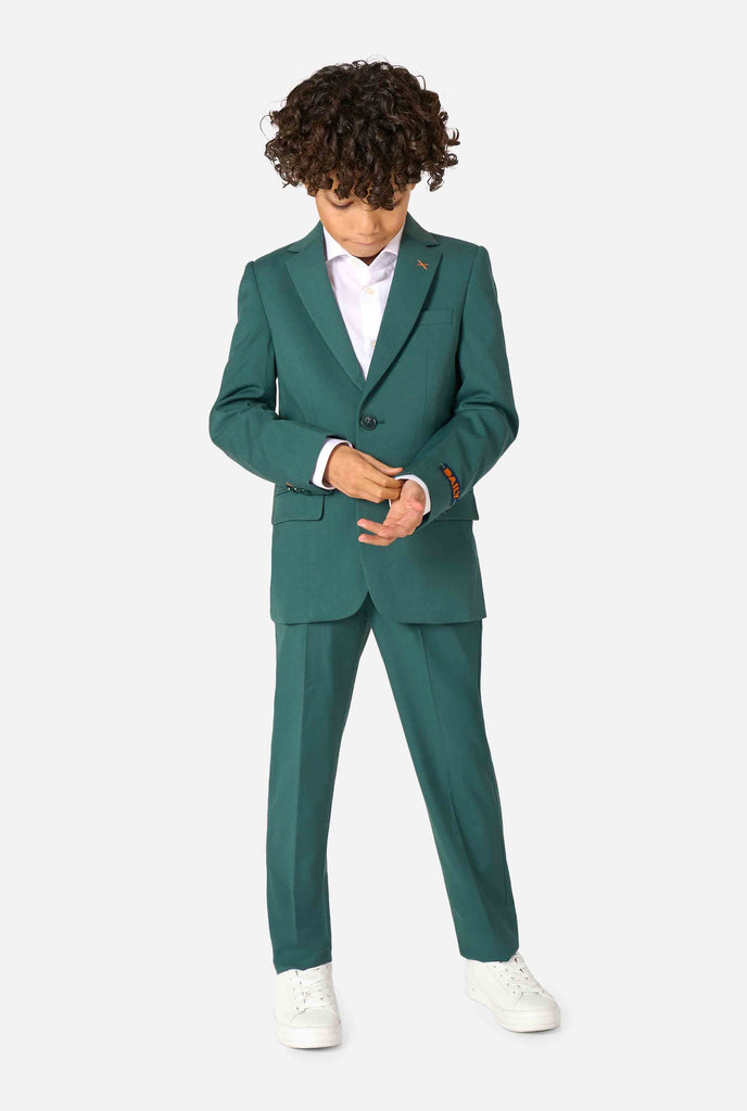 Een kind in een stijlvol donkergroen pak met een wit overhemd, wegkijkend van de camera. Perfecte formele outfit voor speciale gelegenheden, bruiloften en feestjes voor jongens. Volledig lichaam.