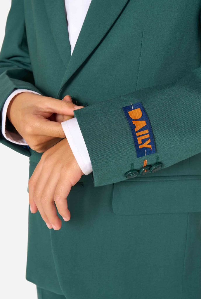 Een kind in een stijlvol donkergroen pak met een wit overhemd, wegkijkend van de camera. Perfecte formele outfit voor speciale gelegenheden, bruiloften en feestjes voor jongens. Close up van de mouwen.