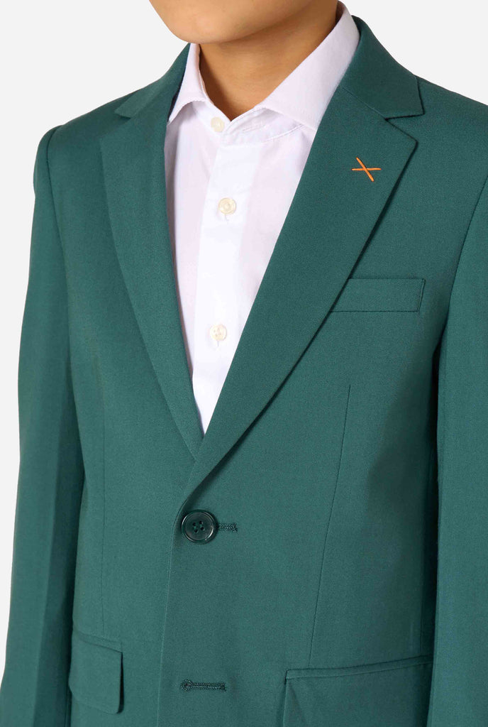 Een kind in een stijlvol donkergroen pak met een wit overhemd, wegkijkend van de camera. Perfecte formele outfit voor speciale gelegenheden, bruiloften en feestjes voor jongens. Close up van de borst.