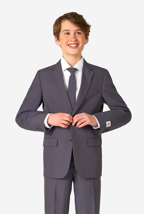 Een tienerjongen in een stijlvol antracietgrijs pak met een wit overhemd, vol zelfvertrouwen lachend. De perfecte formele outfit voor speciale gelegenheden, bruiloften en feestjes.