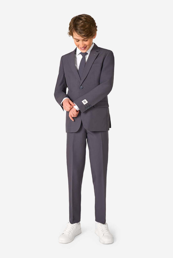 Een tienerjongen in een stijlvol antracietgrijs pak met een wit overhemd, vol zelfvertrouwen lachend. De perfecte formele outfit voor speciale gelegenheden, bruiloften en feestjes.