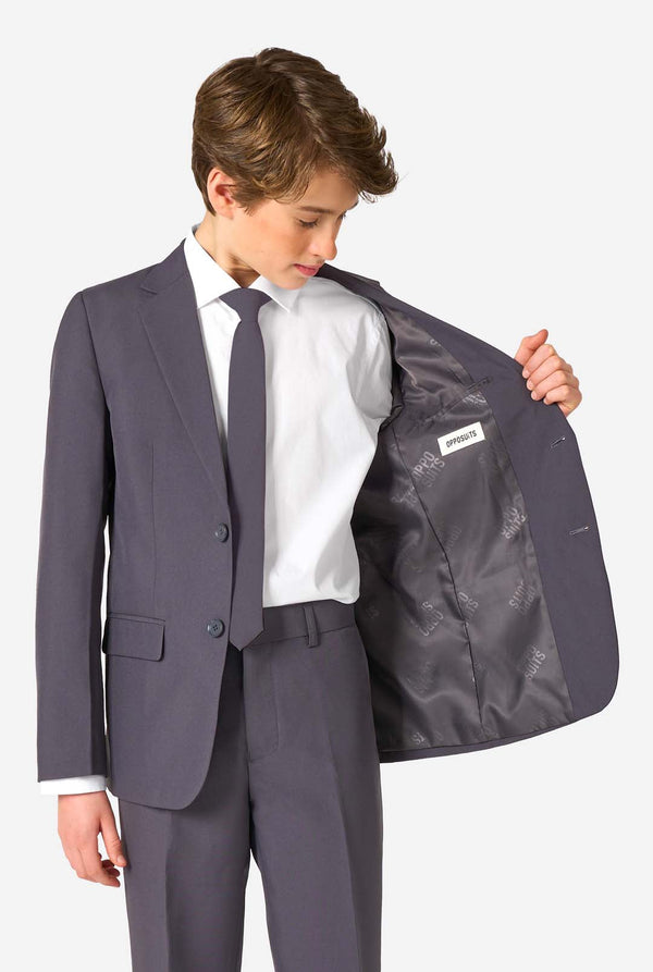 Een tienerjongen in een stijlvol antracietgrijs pak met een wit overhemd, vol zelfvertrouwen lachend. De perfecte formele outfit voor speciale gelegenheden, bruiloften en feestjes.