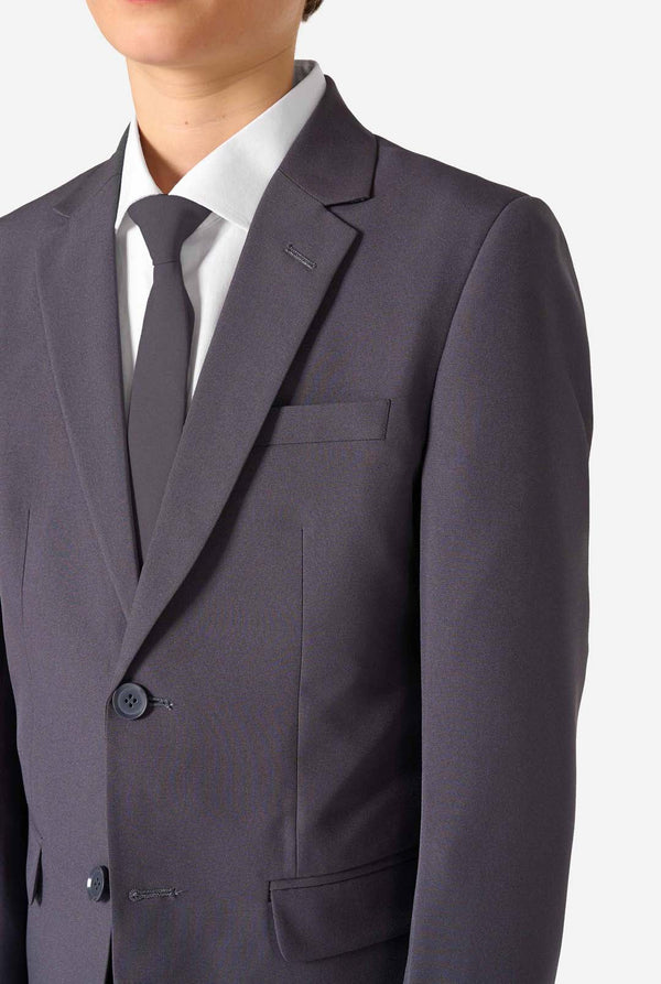 Een tienerjongen in een stijlvol antracietgrijs pak met een wit overhemd, vol zelfvertrouwen lachend. De perfecte formele outfit voor speciale gelegenheden, bruiloften en feestjes.