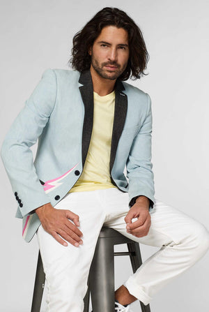 Blauwe casual blazer met witte en roze bliksemschicht gedragen door man zittend op een kruk