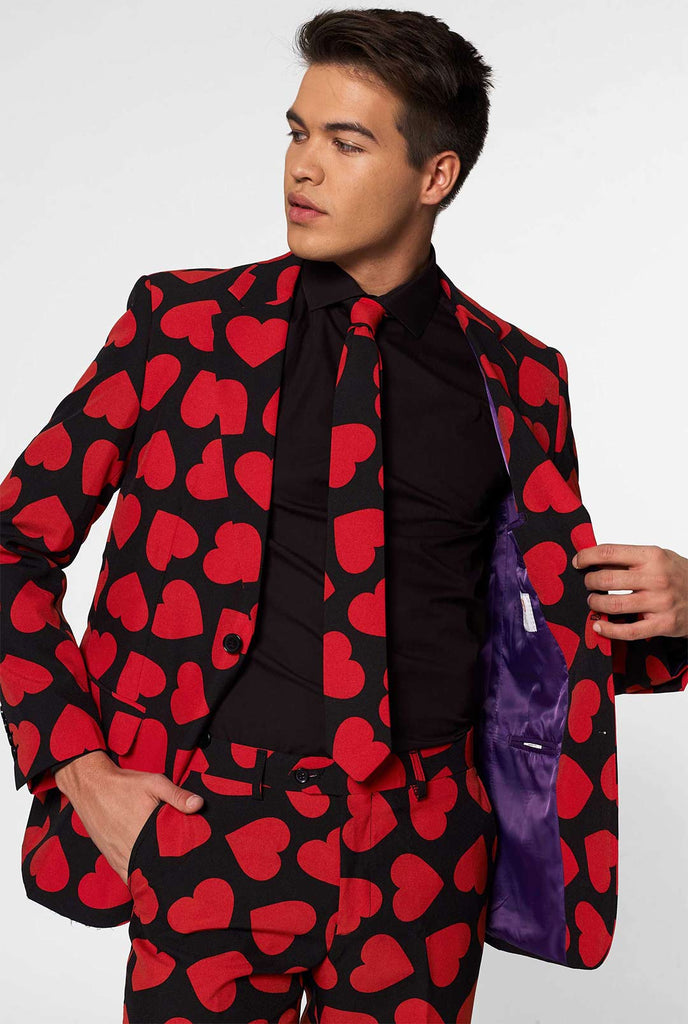 Man draagt ​​een zwart pak met rode harten print